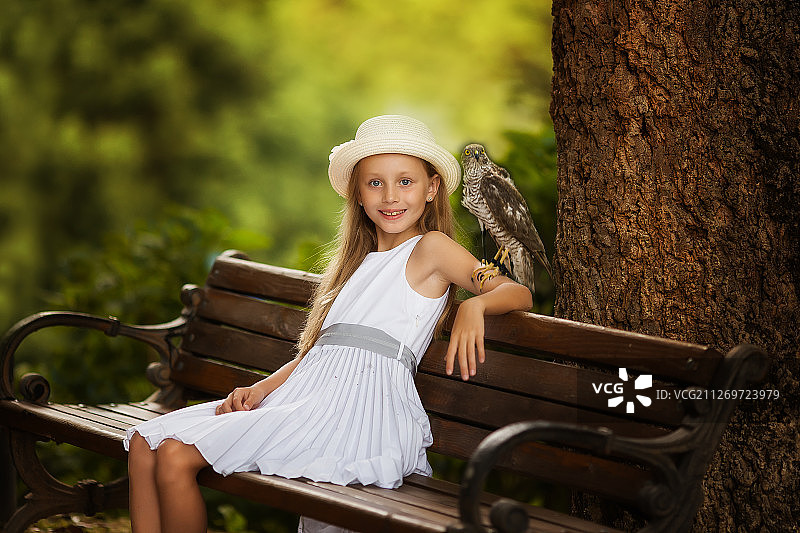 女孩和小鸟坐在公园的长椅上图片素材