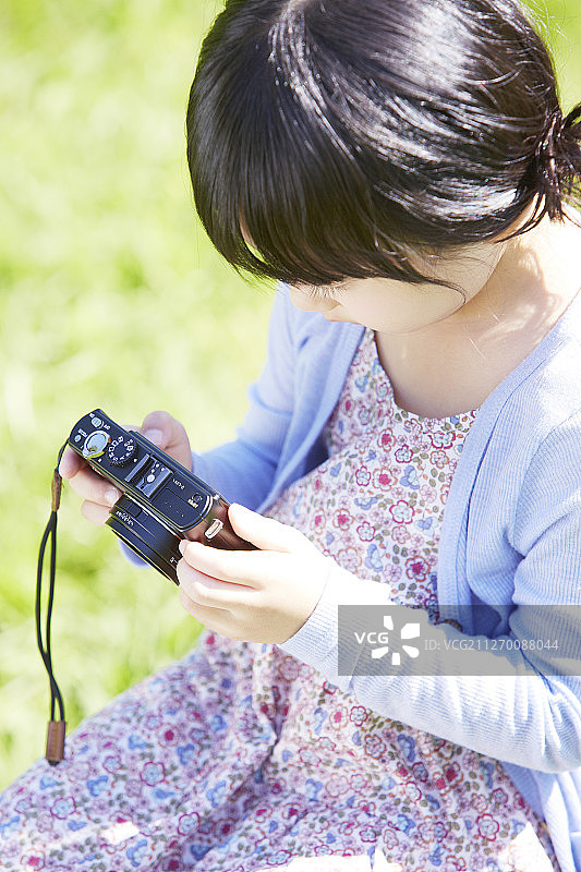 小女孩拿着相机在公园里拍照图片素材