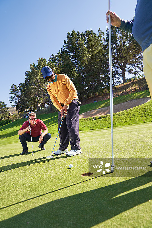 男高尔夫球手把阳光明媚的高尔夫果岭图片素材