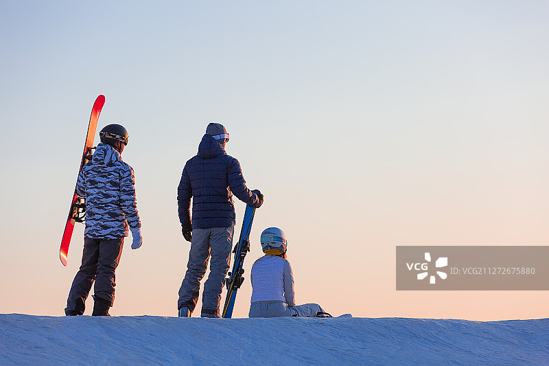 三个青年男女拿着滑雪板在户外滑雪场休息图片素材