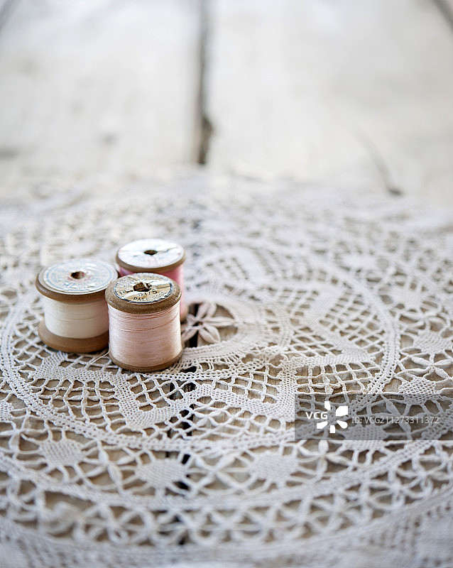 复古的棉花卷轴在一个老式的蕾丝桌布上图片素材