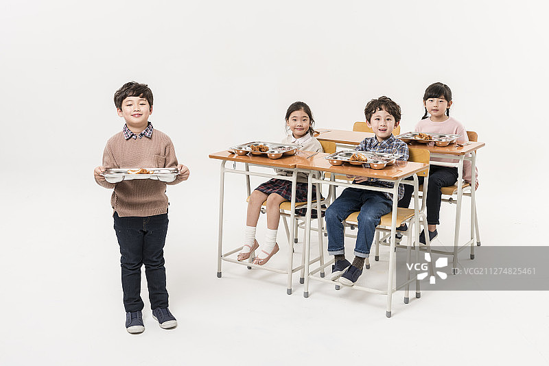 一群孩子坐在课桌旁吃午饭的照片图片素材
