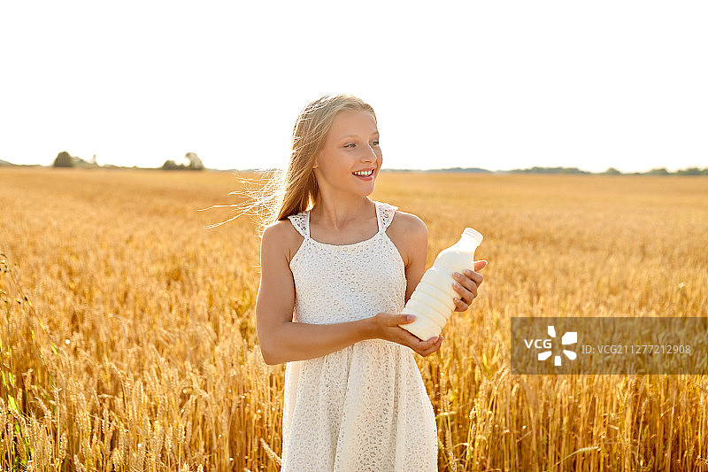 自然，健康的饮食和有机的概念-微笑的小女孩拿着一瓶牛奶在麦田里夏天。在麦片地里，快乐的女孩拿着一瓶牛奶图片素材