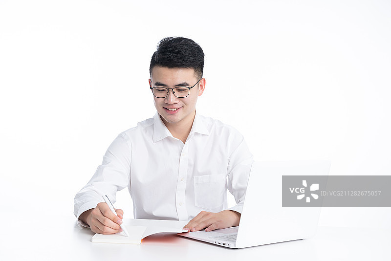 一位亚洲的年轻男性坐在桌子后使用电子设备图片素材
