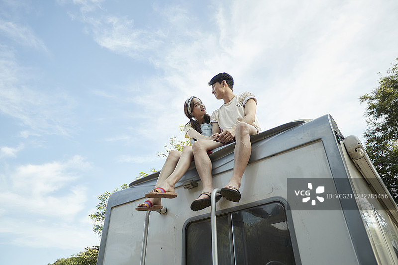 一对夫妇坐在露营车的车顶上看着对方的照片图片素材