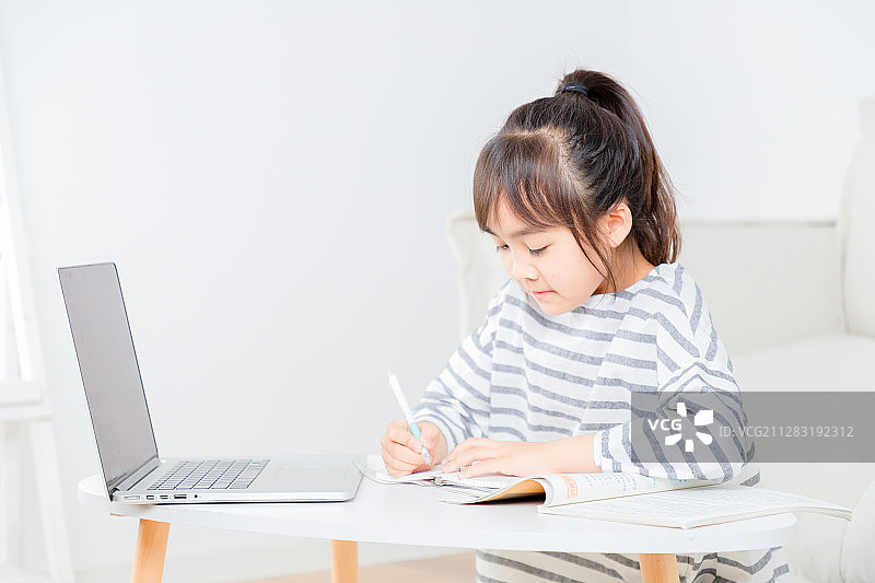坐在地毯上上网课的亚洲小女孩图片素材