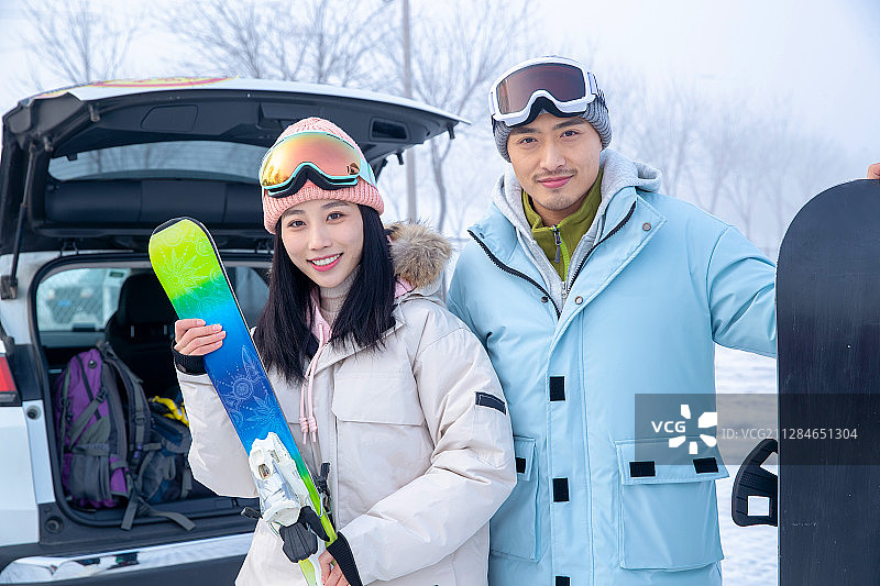 快乐的青年伴侣拿着滑雪板站在一起图片素材