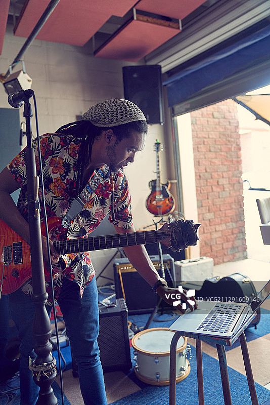 男音乐家在录音棚车库带着笔记本电脑和吉他图片素材