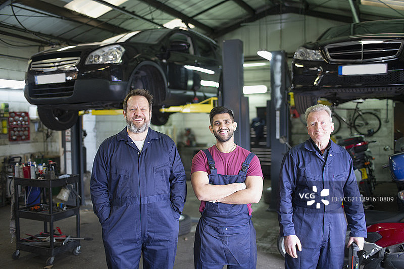 肖像自信的男性机械师在汽车修理店图片素材