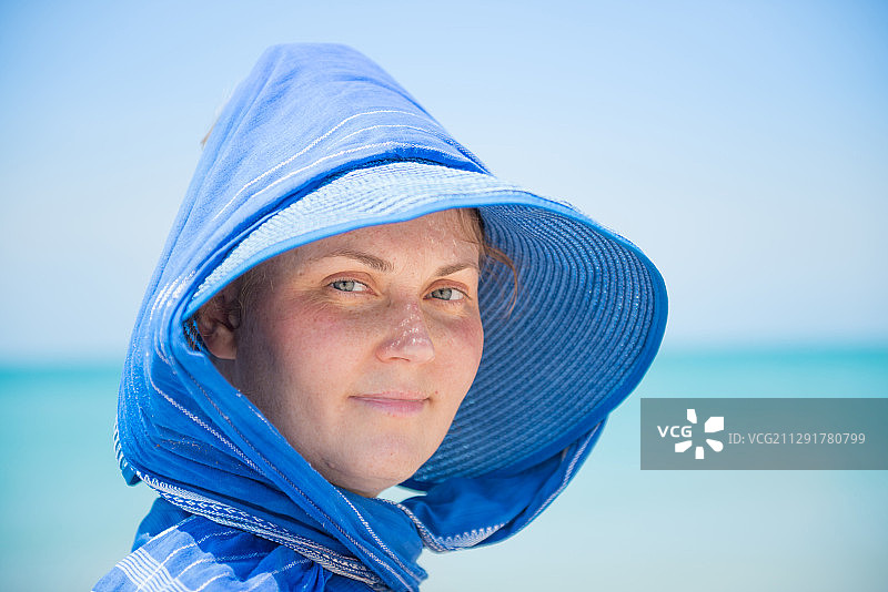 一个戴着蓝色帽子的女人的肖像，背景是大海图片素材