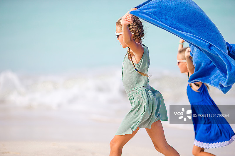 两个女孩在沙滩上玩毛巾，安提瓜和巴布达图片素材