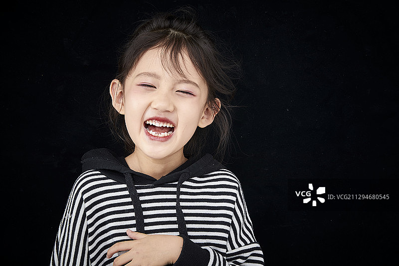 黑色背景前灿烂笑容的亚洲可爱儿童图片素材
