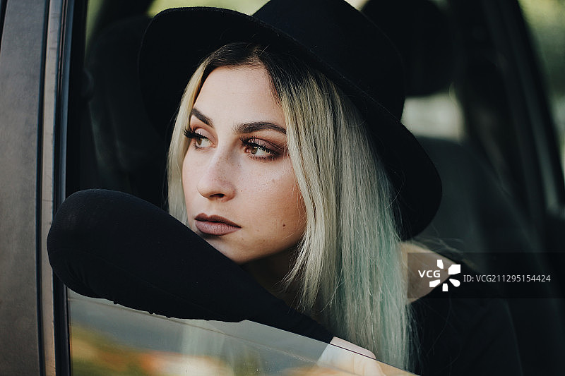 塞尔维亚库尔平，一名年轻的白人妇女戴着黑帽子从车窗探出身子图片素材