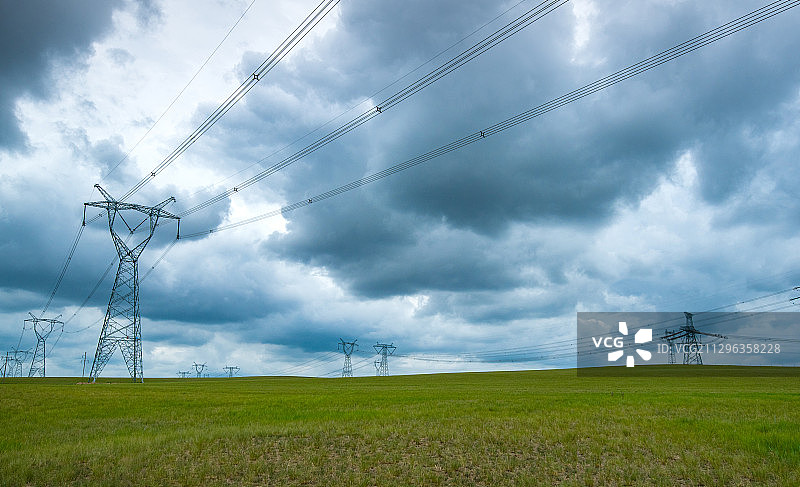 乌云下草原上的高压电线塔图片素材