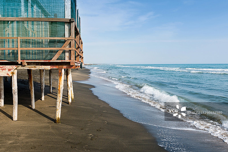 风景与大海，黑色沙滩和白色和蓝色条纹海滩房子，意大利图片素材