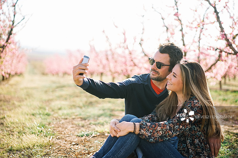 西班牙莱利达，一对快乐浪漫的情侣在户外用手机拍照图片素材