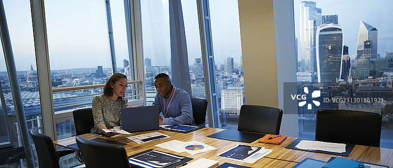 商务人员使用笔记本电脑在高层会议室开会图片素材