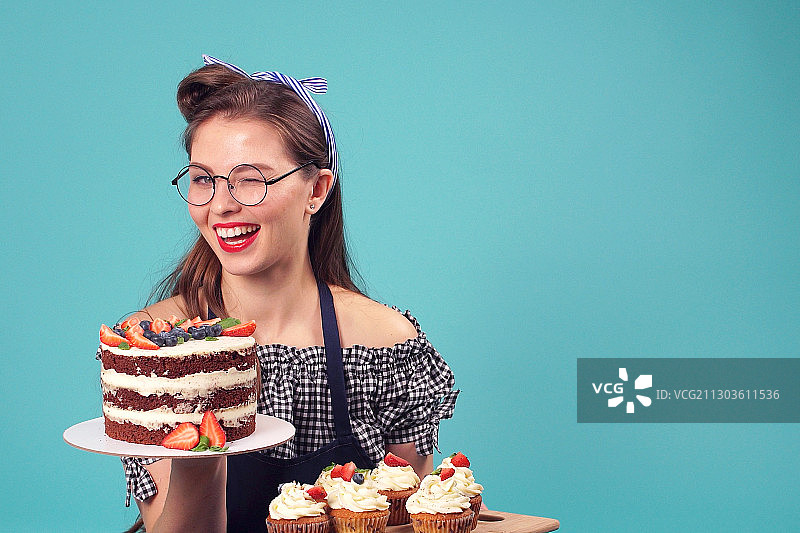 微笑的女人拿着蛋糕在蓝色的背景图片素材