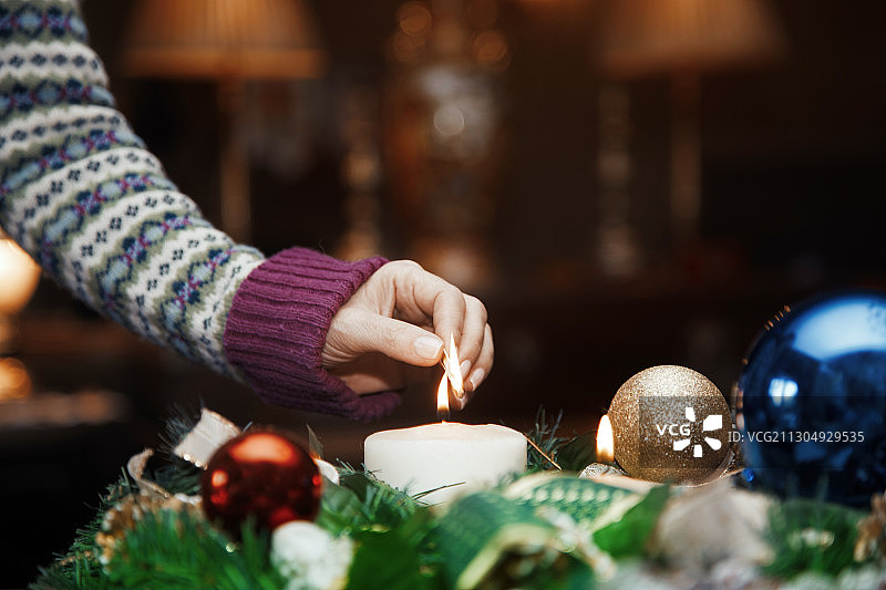 女人的手点燃一支蜡烛在圣诞节的中心装饰图片素材