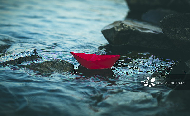 红色的纸船漂浮在深蓝色的湖中图片素材