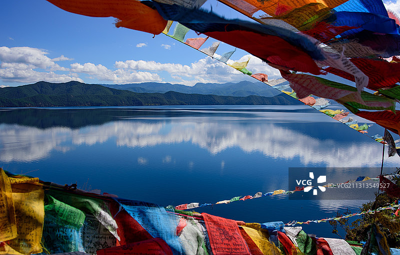 平静如镜的泸沽湖上飘扬着五彩经幡图片素材