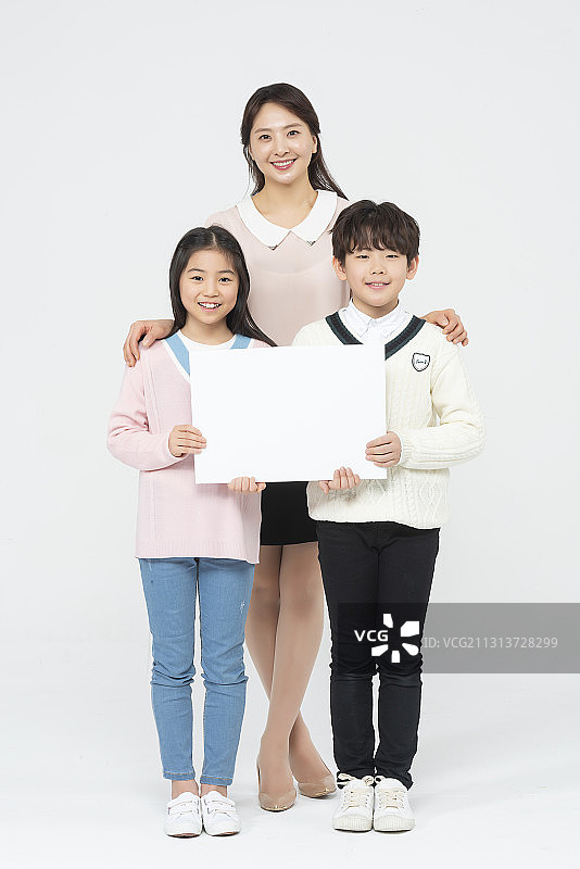 老师站在中间，两个孩子手挽着手围着白色的空白横幅站着图片素材
