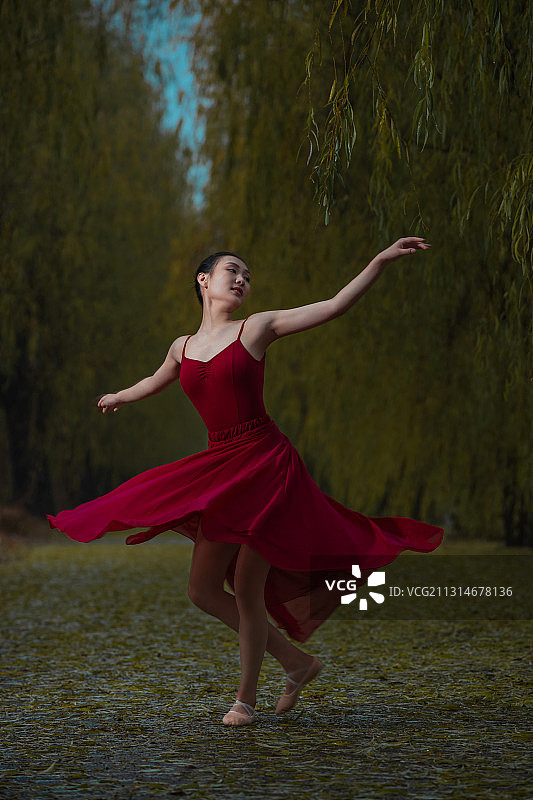 穿红色裙子的青年女人在户外跳芭蕾舞图片素材