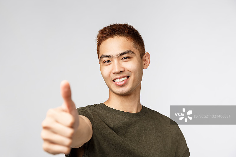 在白色背景下，微笑的年轻人竖起大拇指的肖像图片素材