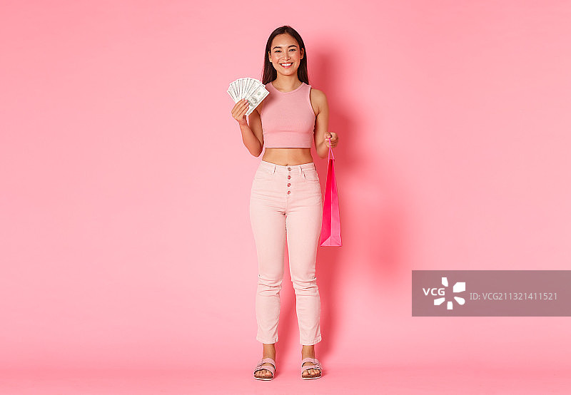 微笑的女人拿着药瓶的肖像，而站在粉红色的背景图片素材