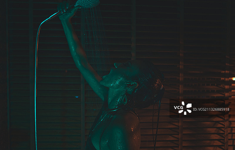 在泰国清迈的一家酒店里，一个年轻女子从淋浴喷头往自己身上浇水图片素材