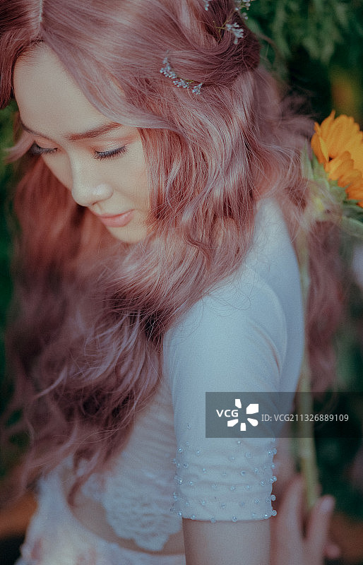 年轻的亚洲女人与粉红色的头发在自然与花图片素材