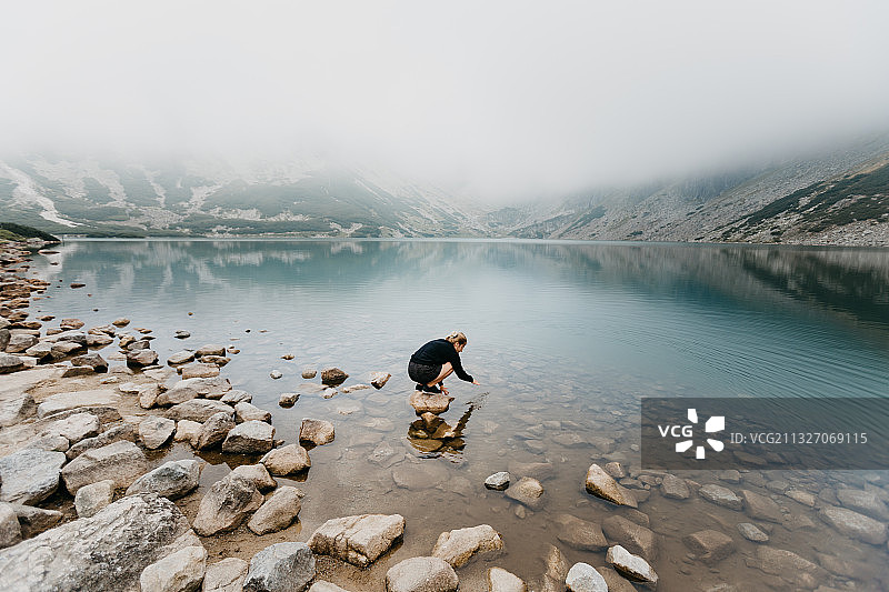 波兰扎科帕内，一名女子坐在山中的湖边图片素材