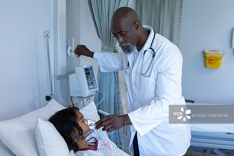 非裔美国男医生在病床上给生病的混血女孩戴上氧气面罩呼吸机图片素材