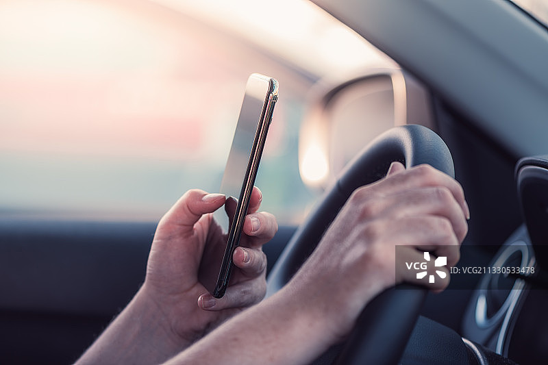 塞尔维亚，一个女人在车里用手机发短信图片素材