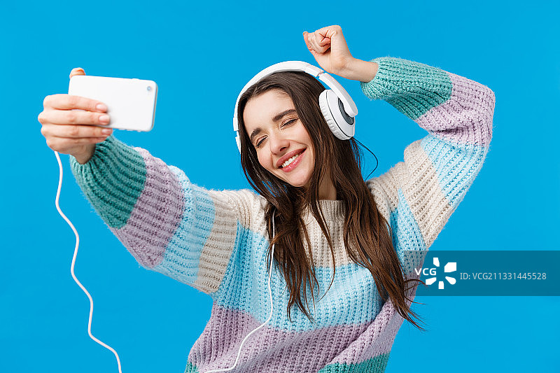 快乐的年轻女子戴着耳机听音乐图片素材