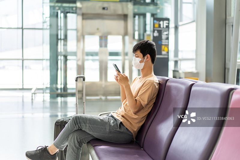 戴着口罩在机场候机的独自旅行者图片素材