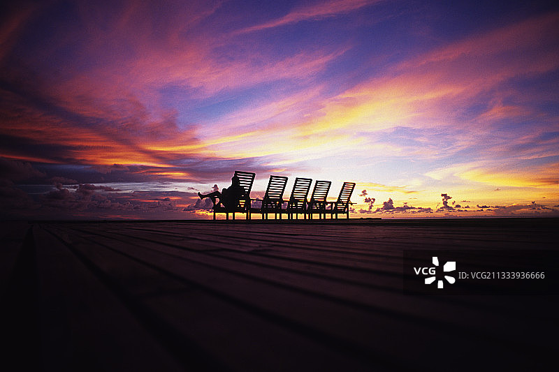 马来西亚日落时分，一个女人坐在平底船上的躺椅上图片素材