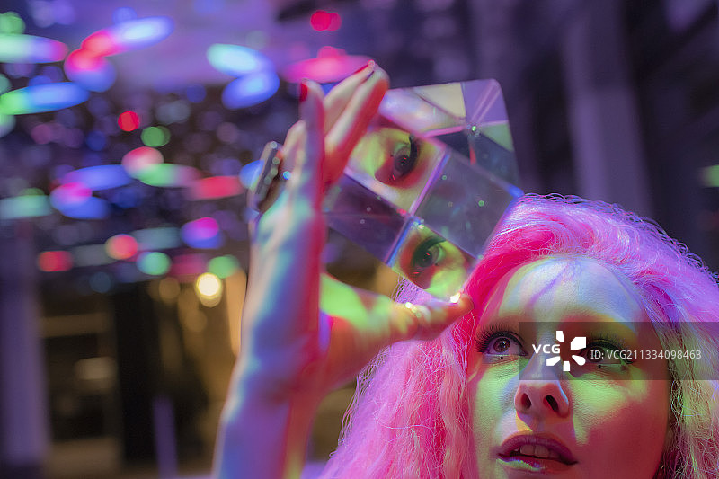 粉红色头发的女人抬头看着立体水晶立方体图片素材