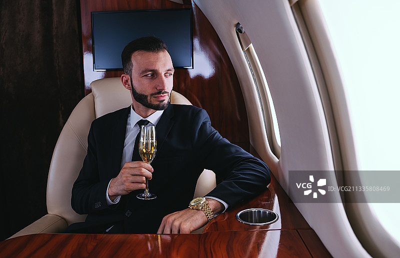 穿着西装在私人飞机上喝香槟的商人图片素材