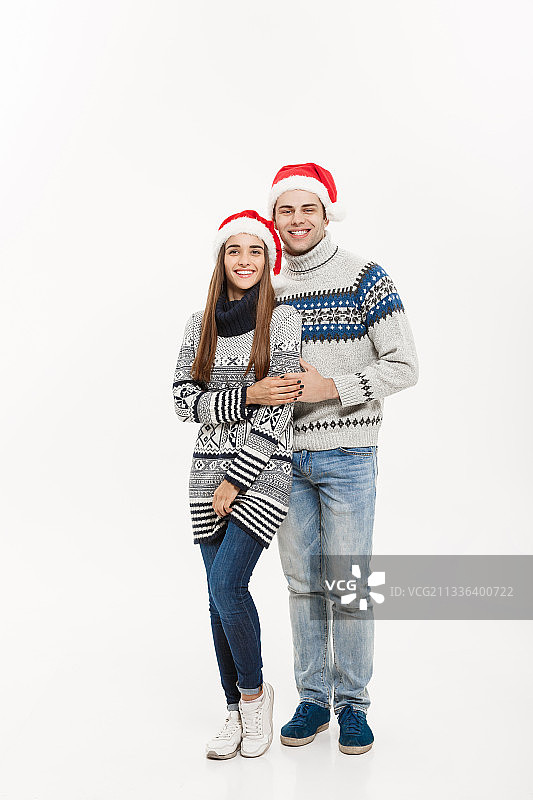 一对夫妇戴着圣诞老人帽，站在白色的背景下图片素材