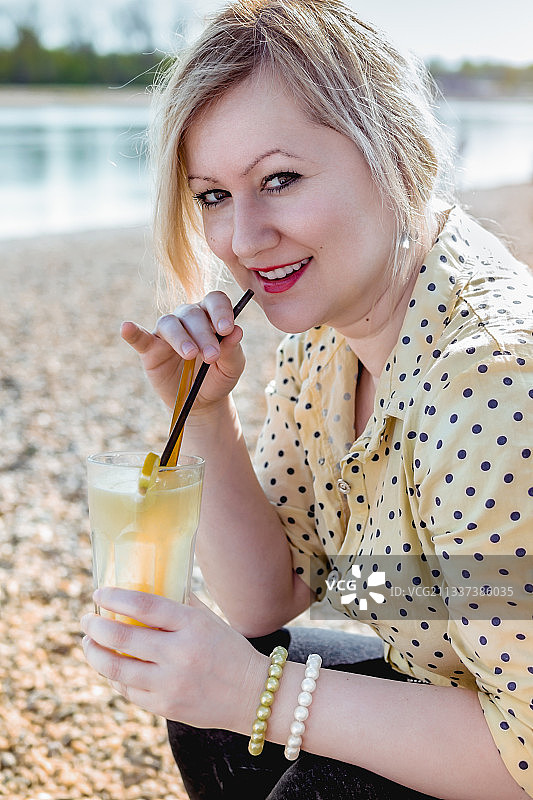 塞尔维亚海滩上微笑的女人拿着饮料的肖像图片素材