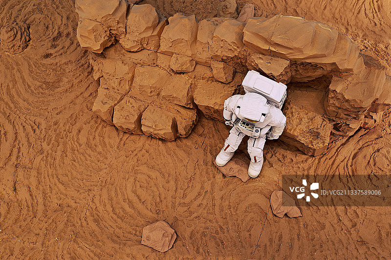 宇航员坐在火星岩石上休息图片素材