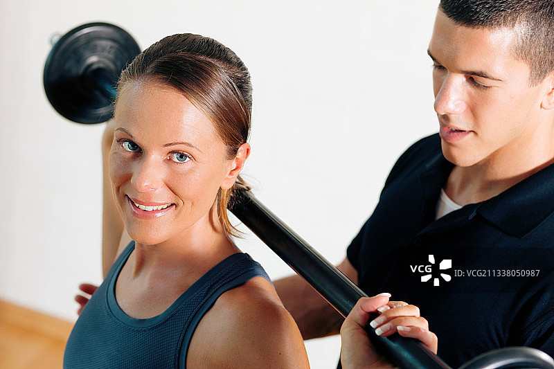 女人和她的私人健身教练在健身房锻炼力量体操与杠铃图片素材