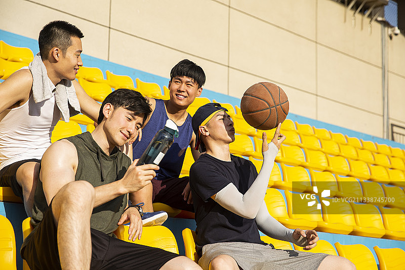 四个青年男子准备打篮球坐在学校操场看台休息图片素材