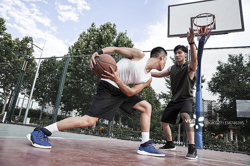 两个青年男子在学校篮球场打篮球比赛图片素材