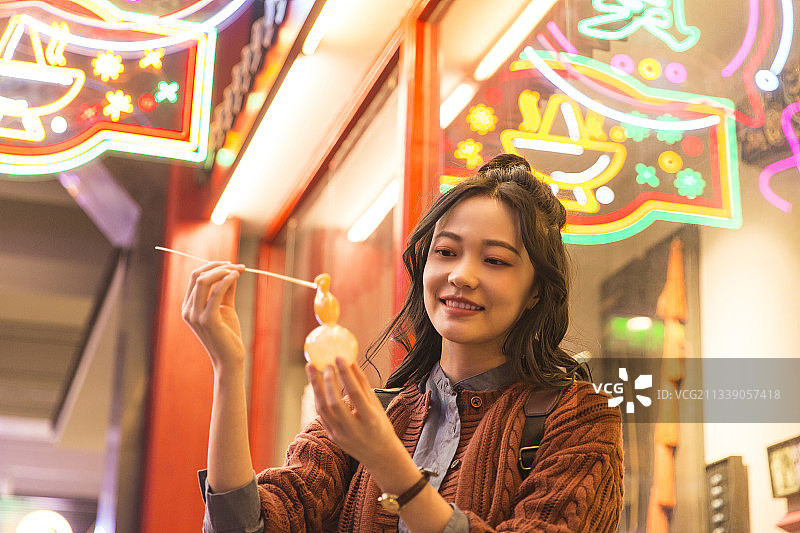 青年女子城市美食街旅行吹糖人图片素材