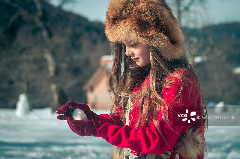 年轻女子穿着暖和的衣服站在雪地上图片素材