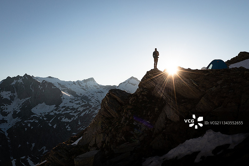 日落时分，站在岩石上的男子剪影，在晴朗的天空下，瑞士泰辛图片素材