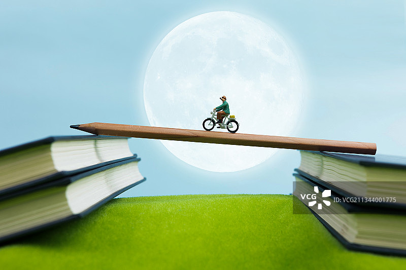微缩景观人群在月光下骑车在书本上通过铅笔旅行图片素材