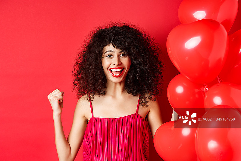 微笑的年轻女子肖像与红色的气球站在红色的背景图片素材